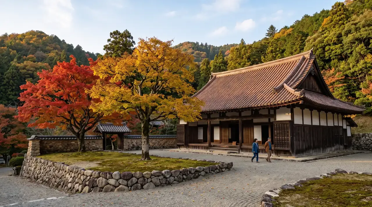 El aula magna de la escuela Shizutani Gakkō en otoño, con su tejado curvo cubierto de tejas de Bizen-yaki de tono pardo rojizo, los dos árboles de Confucio delante, uno con la hoja roja y el otro dorada, y el muro curvo de cantos rodados que cierra el recinto