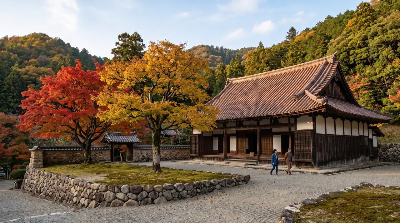 El aula magna de la escuela Shizutani Gakkō en otoño, con su tejado curvo cubierto de tejas de Bizen-yaki de tono pardo rojizo, los dos árboles de Confucio delante, uno con la hoja roja y el otro dorada, y el muro curvo de cantos rodados que cierra el recinto